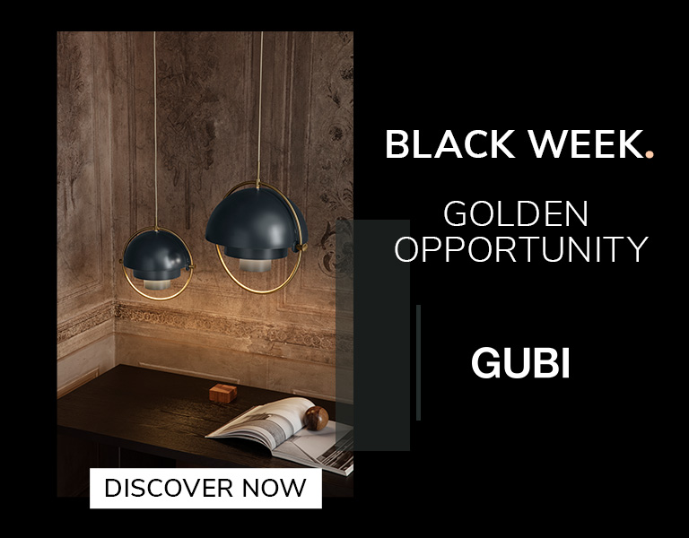 Two modern pendant lamps with dark blue domes and gold accents hanging above a wooden desk in a warmly lit, ornate room. Text reads: ‘Black Week. Golden Opportunity. GUBI.’ A button says ‘Discover Now.’
