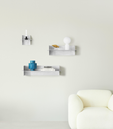 Průhledné nástěnné police Normann Copenhagen s dekorativními doplňky v minimalistickém obývacím prostoru.