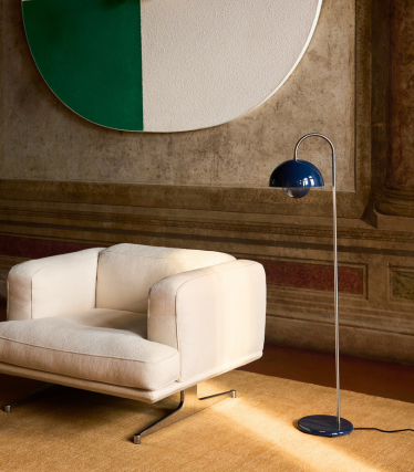 Elegantní stojací lampa &Tradition vedle moderního lounge křesla v útulném interiéru.
